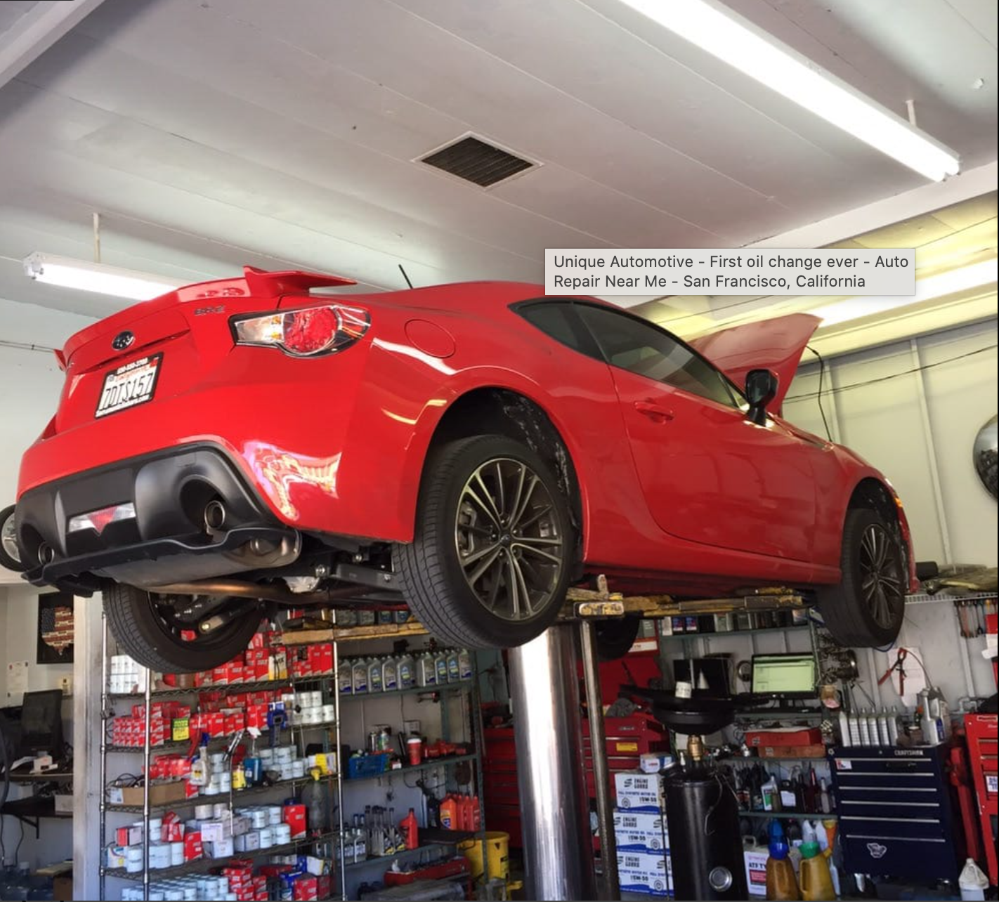 Red Subaru BRZ raised on a lift inside the shop
